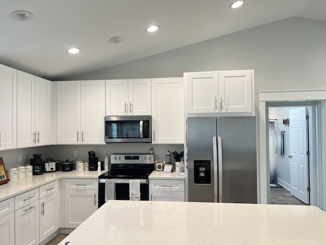 kitchen with stainless steel appliances, white cabinetry, and vaulted ceiling