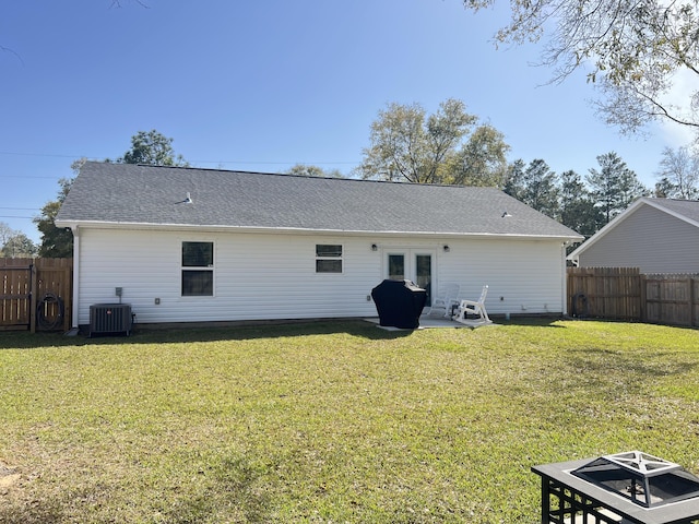 rear view of house featuring a shingled roof, fence, central AC unit, and a lawn