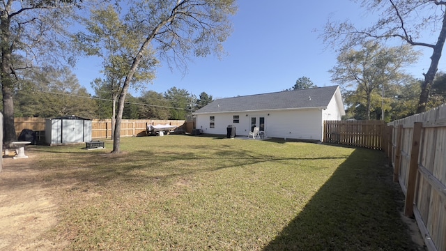 view of yard with an outbuilding, french doors, a fenced backyard, and a storage unit