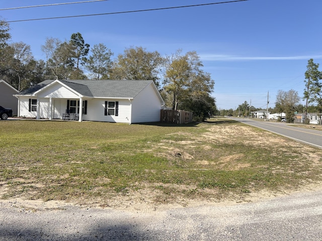 view of property exterior with covered porch, a lawn, and fence