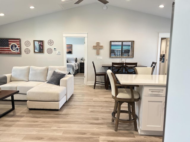 living area with lofted ceiling, a ceiling fan, and light wood-style floors