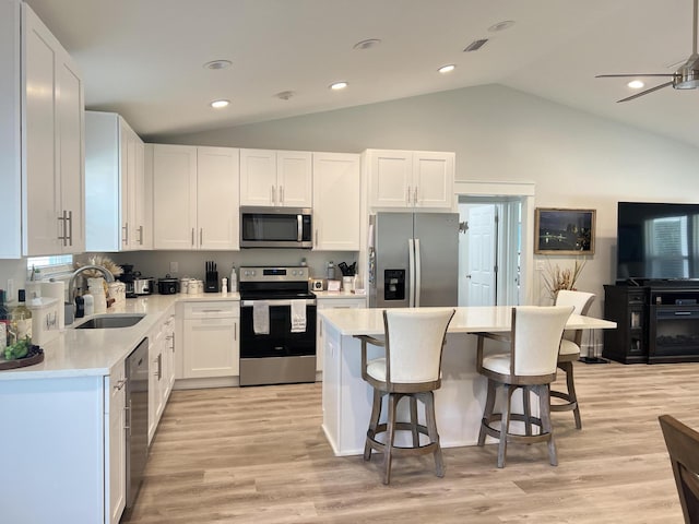 kitchen featuring lofted ceiling, a breakfast bar, stainless steel appliances, light countertops, and a sink