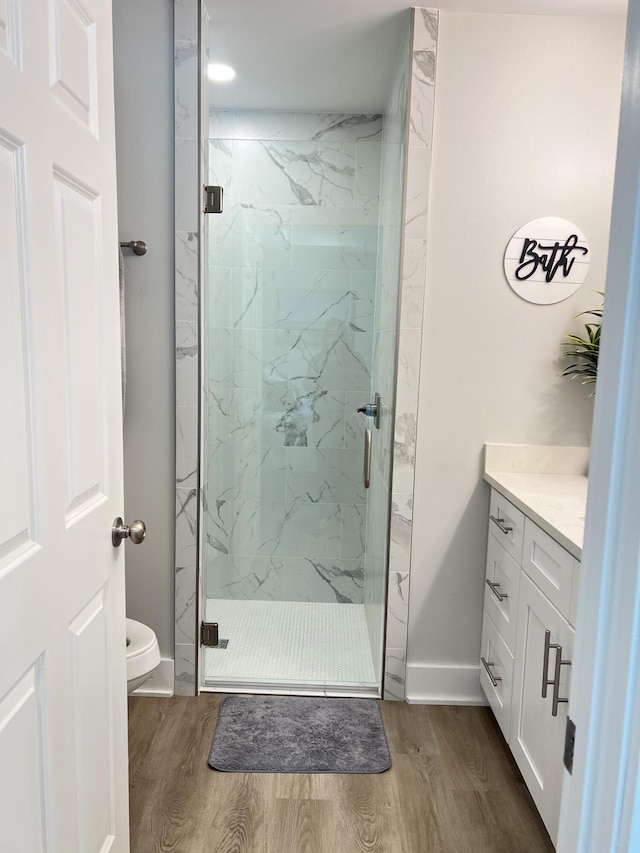 bathroom with a marble finish shower, wood finished floors, and vanity