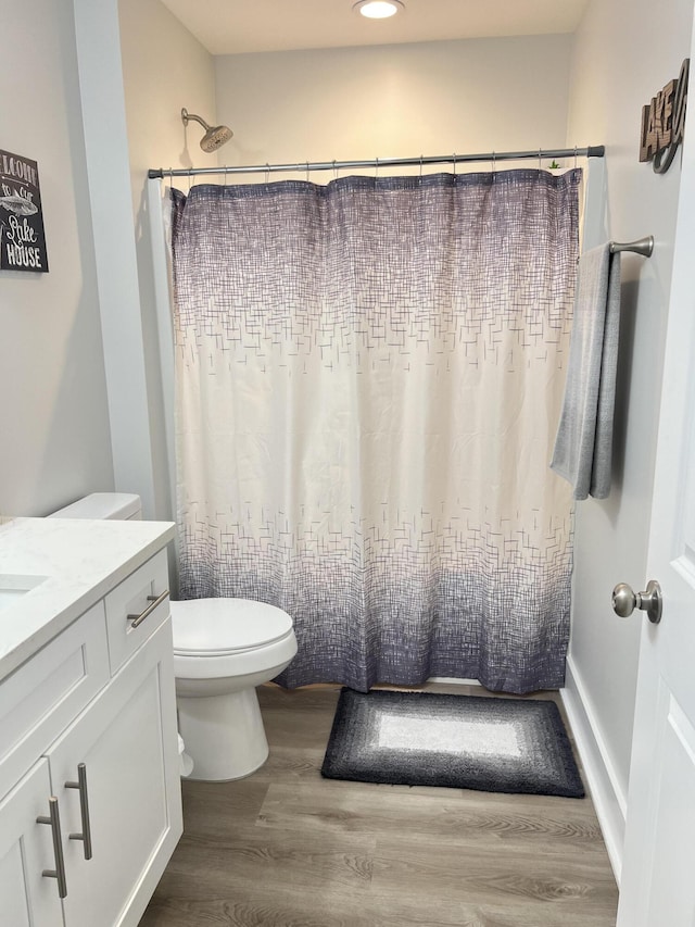 bathroom featuring toilet, a shower with shower curtain, wood finished floors, and vanity