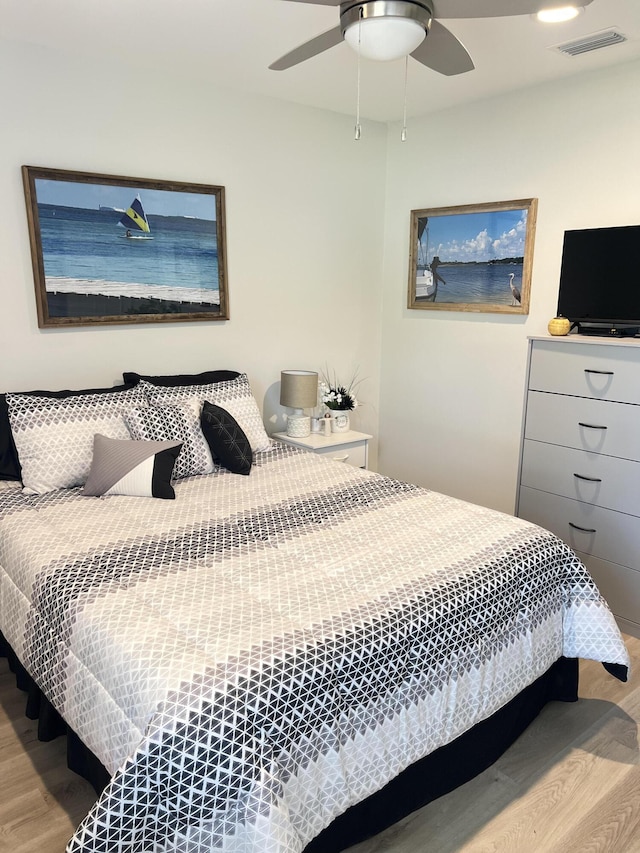 bedroom with a ceiling fan, visible vents, and wood finished floors