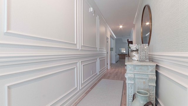 corridor featuring a decorative wall, recessed lighting, light wood-style floors, and a wainscoted wall