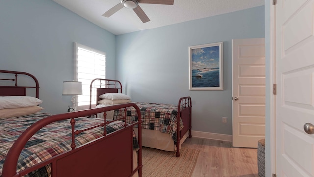 bedroom with ceiling fan, baseboards, and light wood-style flooring