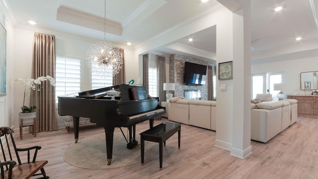 sitting room featuring a raised ceiling, light wood-style flooring, and ornamental molding