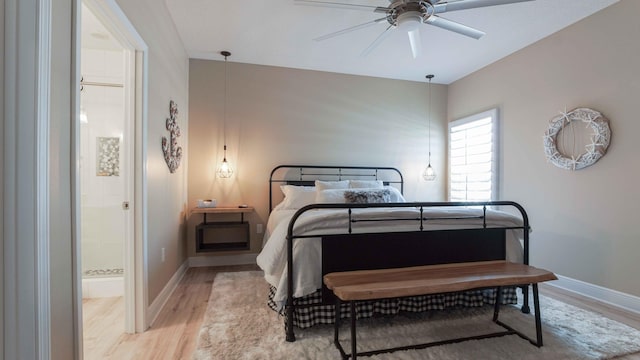 bedroom with baseboards, ceiling fan, ensuite bathroom, and light wood finished floors