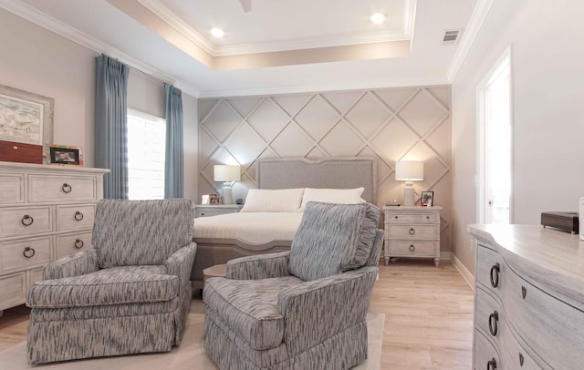 bedroom featuring visible vents, crown molding, an accent wall, light wood-style flooring, and a raised ceiling