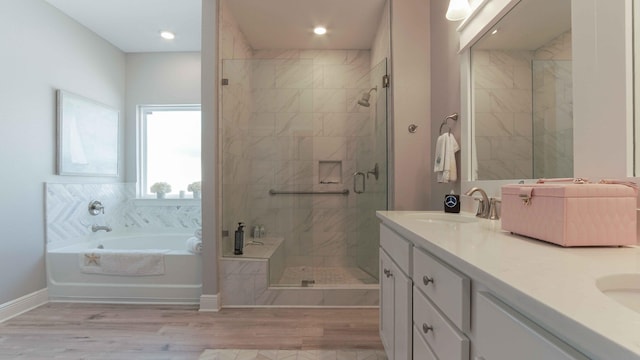 full bathroom featuring a shower stall, double vanity, wood finished floors, a bath, and a sink