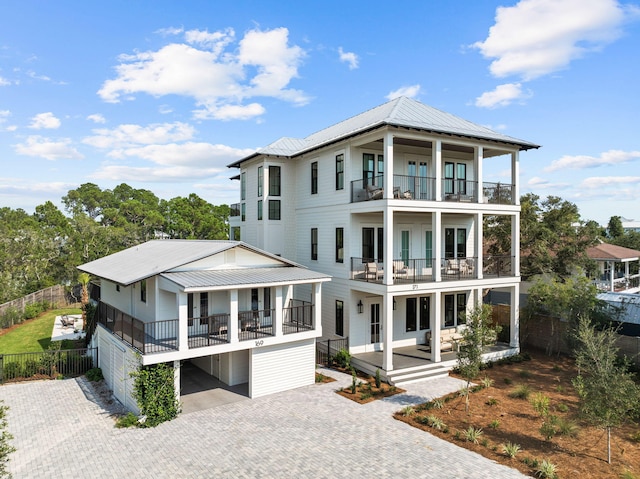 view of front of house featuring a balcony, metal roof, fence, decorative driveway, and a porch