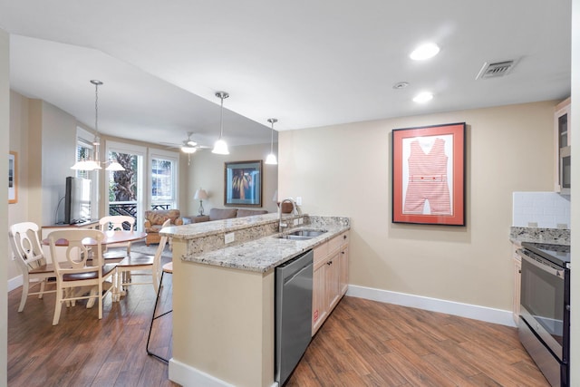 kitchen featuring visible vents, a sink, appliances with stainless steel finishes, a peninsula, and dark wood-style flooring