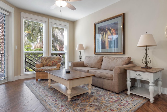 living room with a ceiling fan, baseboards, and wood finished floors