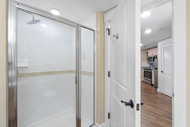 full bath featuring wood finished floors and a shower stall