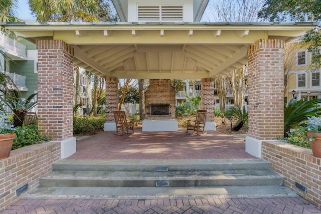 view of patio featuring a gazebo and an outdoor brick fireplace