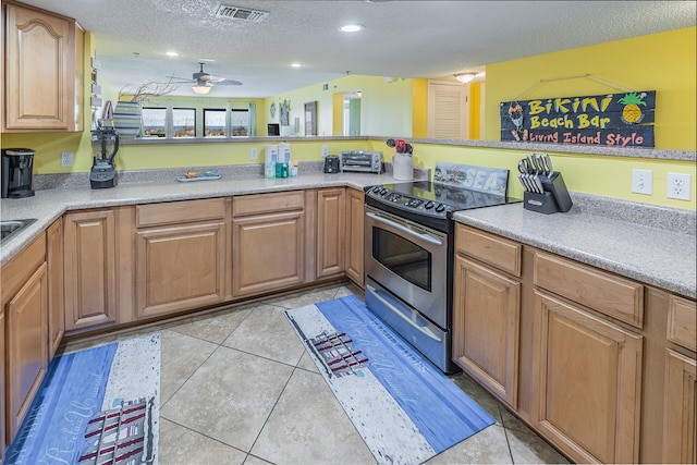 kitchen featuring a textured ceiling, light tile patterned floors, visible vents, and stainless steel range with electric cooktop