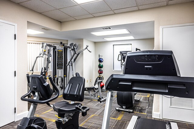 workout area with a paneled ceiling, baseboards, and visible vents