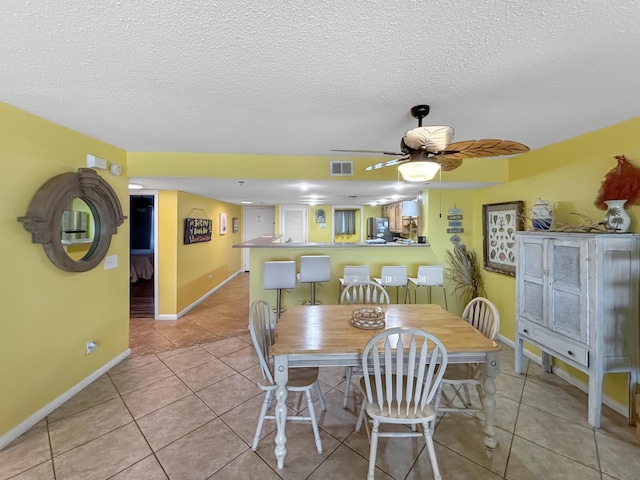 dining room featuring baseboards, visible vents, ceiling fan, tile patterned floors, and a textured ceiling