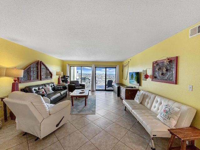 living area featuring light tile patterned floors, visible vents, and a textured ceiling