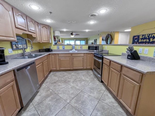 kitchen with light tile patterned floors, appliances with stainless steel finishes, light countertops, a textured ceiling, and a sink