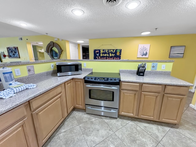 kitchen featuring a textured ceiling, stainless steel appliances, light countertops, and visible vents