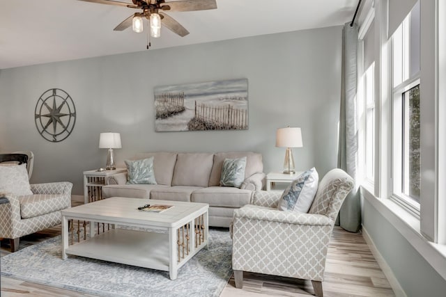 living area featuring a ceiling fan, light wood-style floors, and baseboards