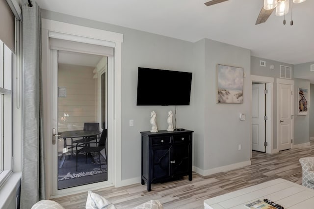 living room with visible vents, baseboards, light wood-style floors, and ceiling fan