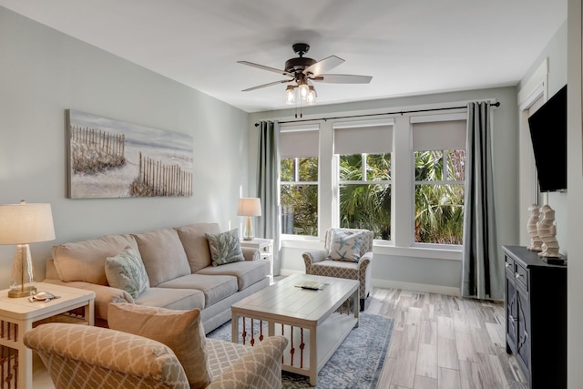 living area featuring baseboards, light wood-style floors, and ceiling fan