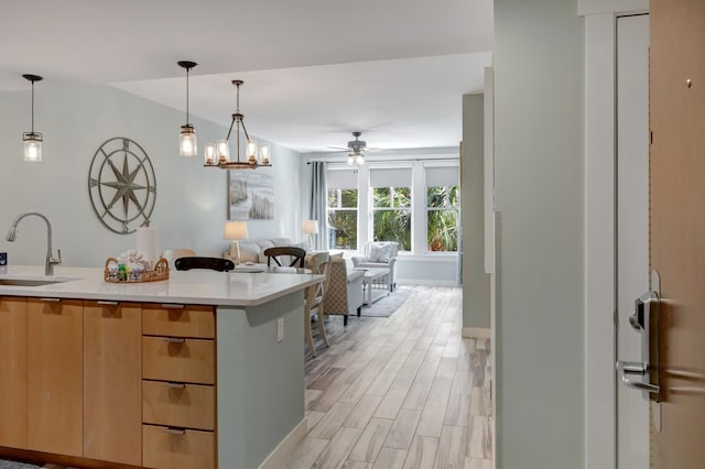 kitchen with light brown cabinetry, a sink, open floor plan, light wood-style floors, and light countertops