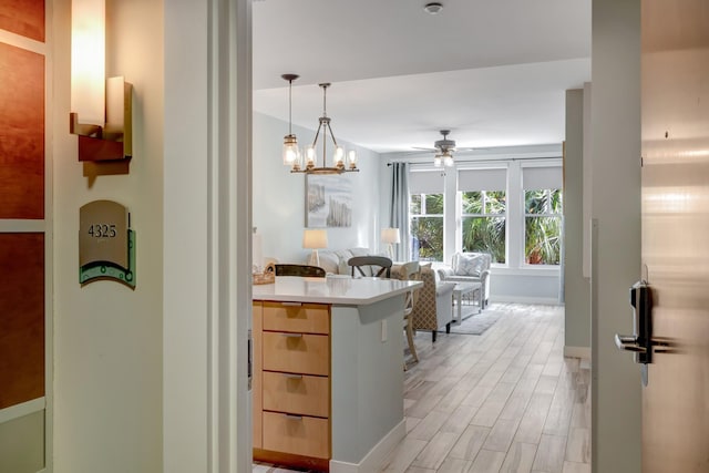 kitchen featuring open floor plan, light countertops, light wood-style flooring, hanging light fixtures, and a ceiling fan