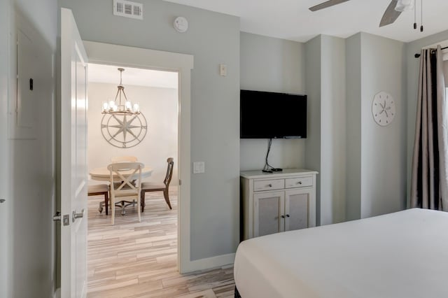 bedroom featuring visible vents, baseboards, light wood-style flooring, and ceiling fan with notable chandelier