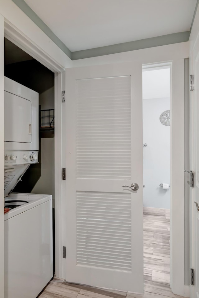 laundry area with light wood finished floors, stacked washer / dryer, and laundry area