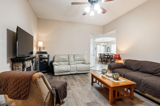 living area featuring a textured ceiling, ceiling fan with notable chandelier, and wood finished floors