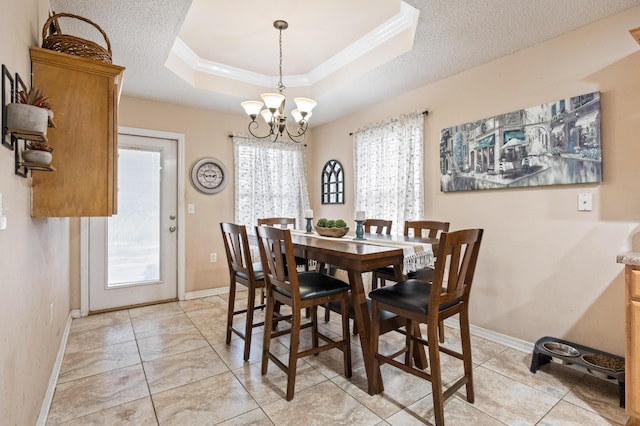 dining area featuring plenty of natural light, a tray ceiling, a chandelier, and crown molding