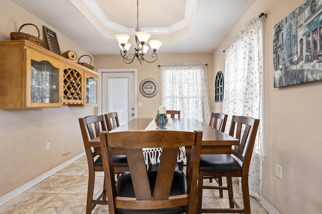 dining room featuring baseboards, a raised ceiling, an inviting chandelier, crown molding, and a textured ceiling