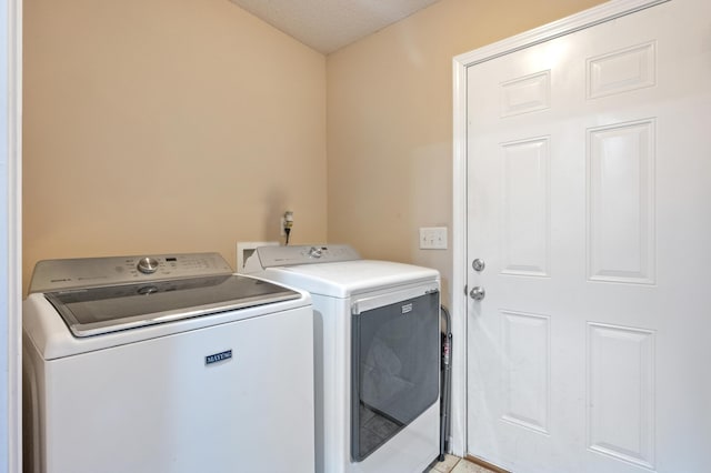 washroom featuring laundry area, washer and clothes dryer, and a textured ceiling