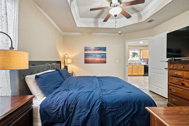 bedroom with crown molding, visible vents, ceiling fan, and a tray ceiling