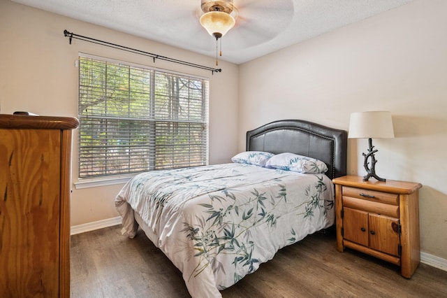 bedroom featuring a ceiling fan, a textured ceiling, baseboards, and wood finished floors