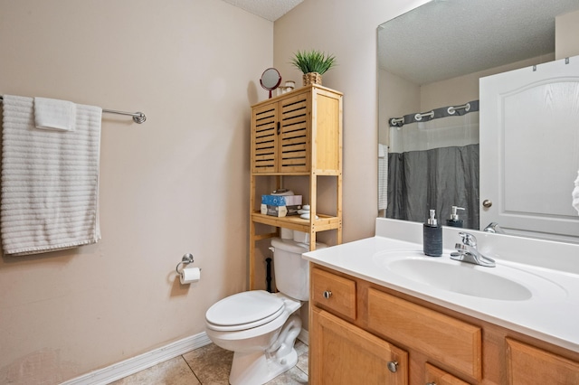 bathroom with baseboards, toilet, tile patterned floors, a textured ceiling, and vanity