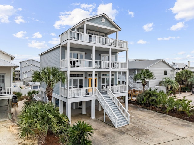 coastal inspired home featuring a balcony, stairway, a carport, and concrete driveway