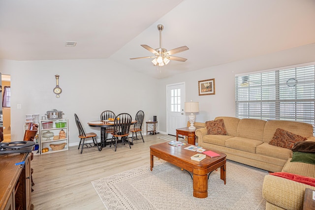 living room with visible vents, ceiling fan, baseboards, lofted ceiling, and light wood-style floors