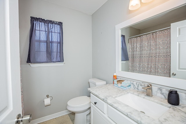 bathroom with vanity, toilet, and baseboards