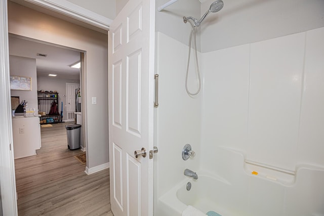 bathroom featuring baseboards, wood finished floors, and  shower combination