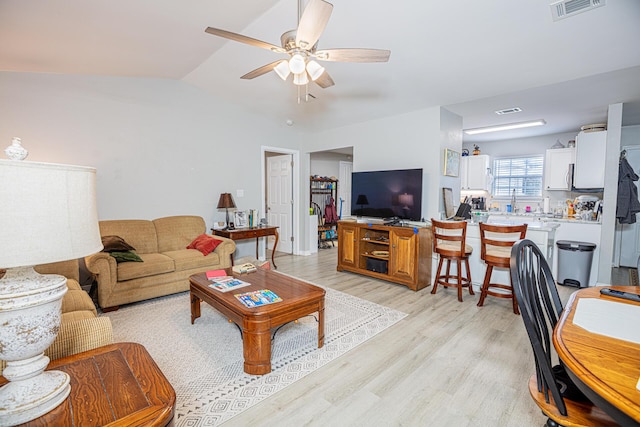 living area with light wood-style floors, a ceiling fan, visible vents, and vaulted ceiling