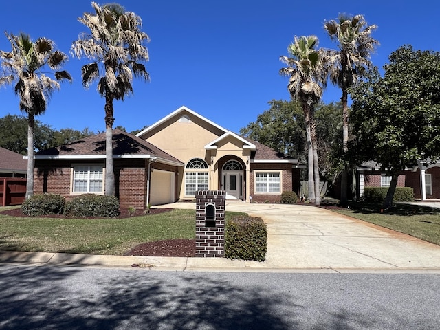 view of front facade with driveway, brick siding, an attached garage, a front yard, and stucco siding