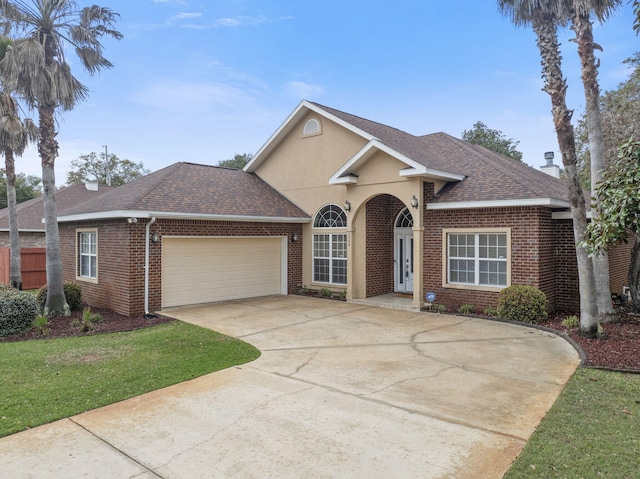 traditional-style house with concrete driveway, an attached garage, brick siding, and a shingled roof