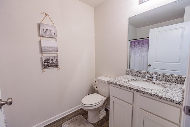 bathroom featuring baseboards, wood finished floors, toilet, and vanity