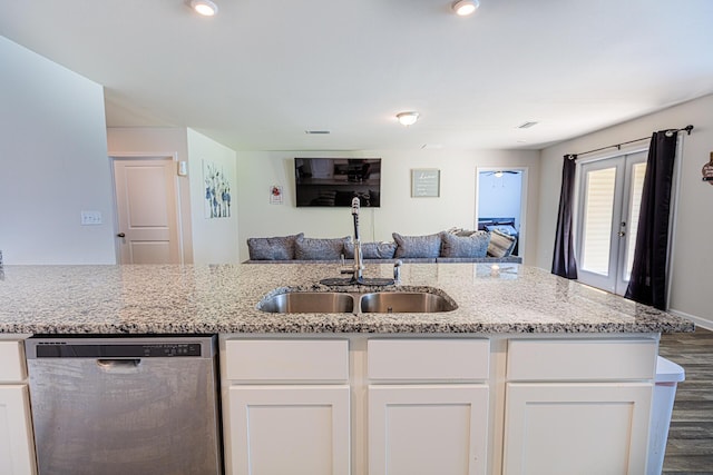 kitchen featuring open floor plan, a sink, dishwasher, white cabinets, and light stone countertops