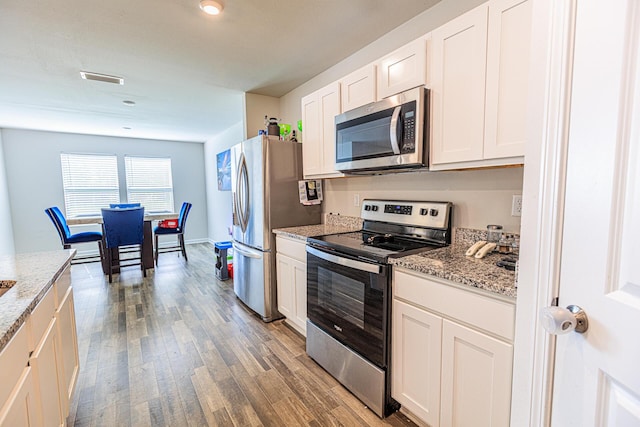 kitchen with light wood-style flooring, light stone counters, visible vents, white cabinets, and appliances with stainless steel finishes